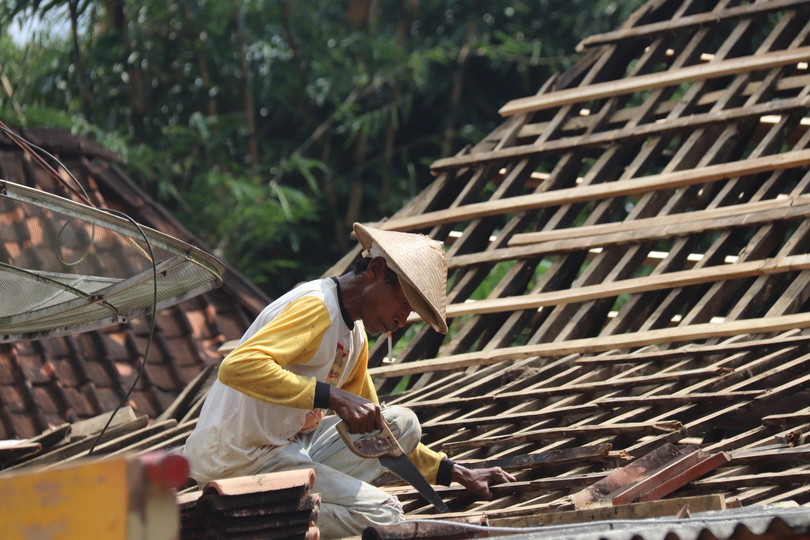 Carpenter framing a wooden roof structure under a bright sky
