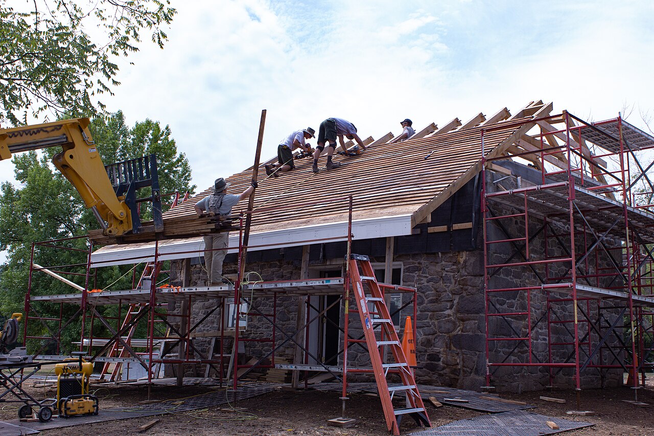 Roofers laying wooden shingles on a new roof slope
